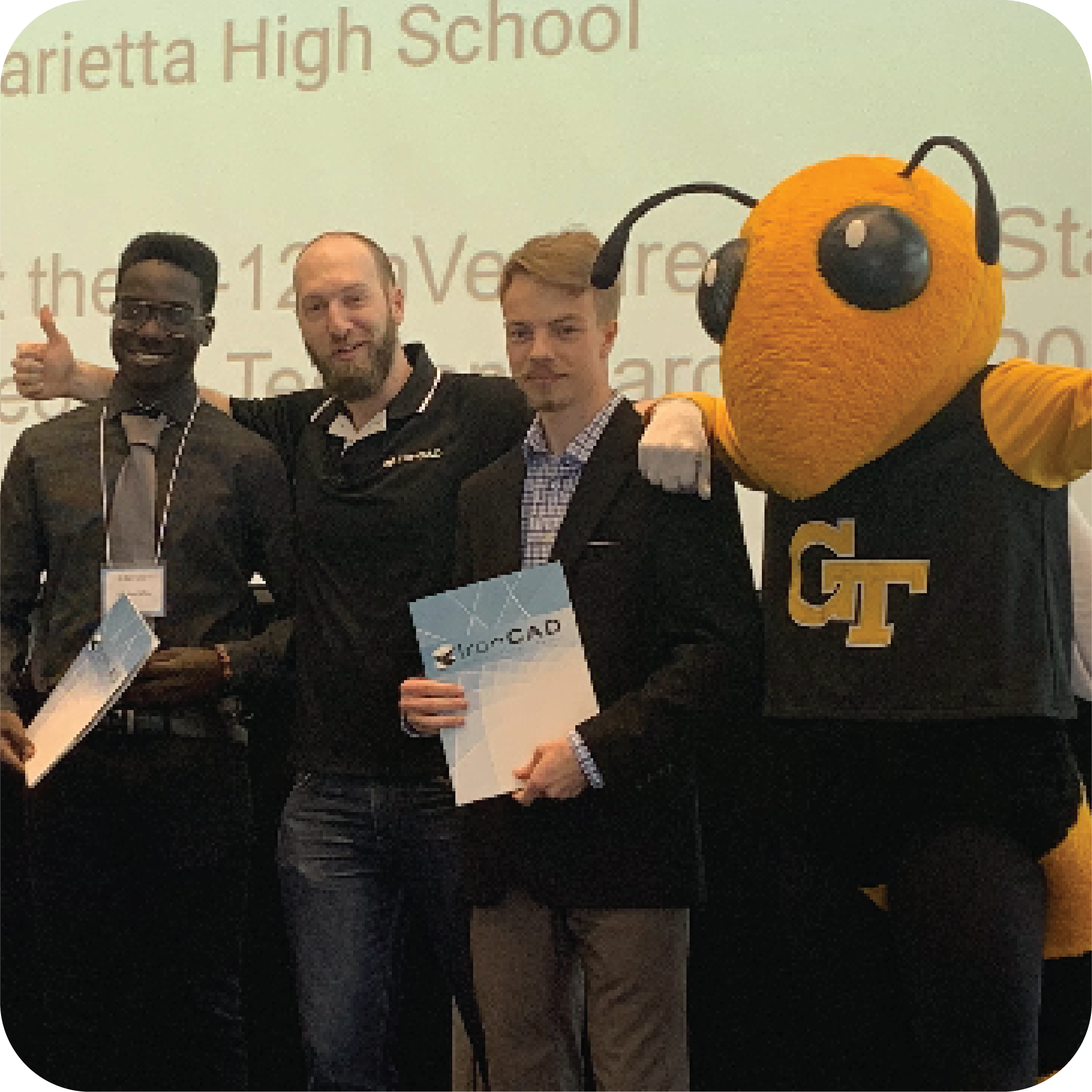 Two smiling students holding prizes and standing next to Buzz (Georgia Tech's yellowjacket mascot) and Cameron Schriner (IronCAD representative).